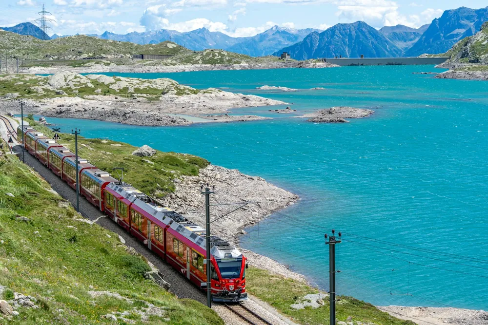 Red Swiss panoramic train crossing a stone viaduct in the mountains
