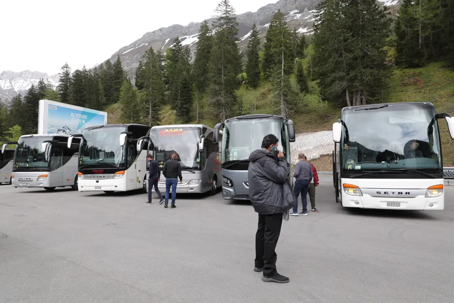 A line-up of coaches in an Alpine parking area